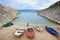 Small motor boats on cozy harbor coast among high rocky shores and young tourist woman