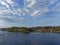 A Small Motorboat cruising past the forested coastline with scattered Houses and Cabins in Bergen Fjord