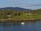 A Small Motorboat cruising past a Navigation Marker beside the forested coastline of Bergen Fjord