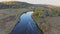 Small motorboat sails on long curvy river running on meadows