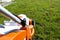 A small motorized electric mower standing on the lawn, it is orange in color.