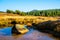 Small mountain creek meandering in the middle of meadows and forest. Sunny day with blue sky and white clouds in Jizera