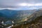 small mountain lake in the form of a heart among snowy glaciers, green mountain ridges overgrown with trees, Chersky peak