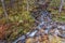 A small mountain rocky rushing stream in the middle of a Scandinavian forest