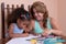 Small multiracial girl and her mother drawing with color pencils