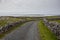 Small narrow asphalt road with beautiful unique views, county Galway, Ireland. Cloudy sky. Irish scenery. Nature landscape.