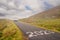 Small narrow asphalt road in Connemara in the mountains area White motor home going up the hill and sign 2023. County Galway,