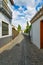 Small narrow street with white houses and abundant greenery in the old European city