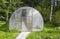 A small new empty polycarbonate greenhouse on a forest background