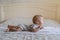 a small newborn baby crawls on the bed and lifts its head up. Space for text,
