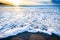 Small ocean sea waves on sandy beach with sunrise sunset.