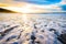 Small ocean sea waves on sandy beach with sunrise sunset.