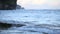 Small ocean waves wash over rocks on the beach at sunset