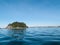 Small off-shore island across blue of ocean from low point of view with Mount Maunganui