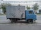 A small old blue shabby abandoned truck for transporting vegetables and fruits abandoned on the lane of vehicles.