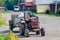 A small old mini tractor with a trailer stands on a rural street