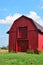 Small old red barn under sunny blue skies on a hot and humid summer day