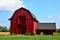 Small old two story red barn with annex under sunny blue skies on a hot and humid summer day