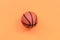 Small orange ball for basketball sport game lies on texture background of fashion pastel orange color paper in minimal concept