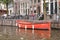 Small orange boat moored at the side of an urban canal quayside