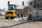 A small orange bulldozer near a pile of sand at a construction site. Construction site near a new house under construction