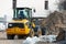 A small orange bulldozer near a pile of sand at a construction site. Construction site near a new house under construction