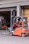 Small orange forklift parked at a warehouse