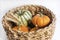 Small organic pumpkins with yellow wheats in a handmade basket on a white background, close up