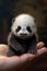 A small panda bear sitting on top of a person's hand. Generative AI image.