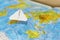 Small paper airplane over a geographical map of the world. selective focus.