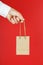 Small paper Bag at arm`s length, brown craft bag for takeaway isolated on red background. Packaging template layout with space fo