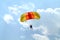 Small parachutist with colourful yelow orange red parachute on parachuting competition