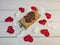 A small parcel with a wax seal tied with twine and many white and red hearts on wooden boards