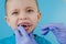 Small patient does not want to open the dentist`s mouth on blue background. Dantist treats teeth. close up view of dentist