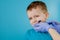 Small patient does not want to open the dentist`s mouth on blue background. Dantist treats teeth. close up view of dentist