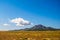 Small peak above arid desert grassland with blue sky overhead.