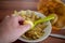 Small peeled potato is held by one hand over a bowl of potato peel