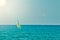 Small personal sailboat sailing in the open flat sea on a summer day