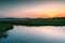 A small picturesque river among a green meadow during sunset. Small river in the countryside.