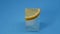Small piece of lemon lies on an ice cube. Still life on a blue background.