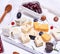 small pieces of brie cheese, roquefort, camembert, cheddar and cheese with walnuts on a white wooden board