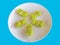 Small Pieces of Green Layered Cake with Toothpicks on White Plate Isolated on Blue Background