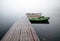 Small pier with boats on lake in foggy morning