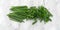 Small pile of cut chives atop a gray marble cutting board