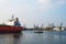 A small pilot ship leads a large red cargo ship at the seaport on a windless autumn day