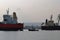 A small pilot ship leads a large red cargo ship at the seaport on a windless autumn day