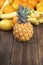 Small Pineapple with other tropical fruits on wood