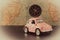 Small pink car with a compass on the roof on a background of vintage maps, travel concept