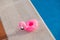 Small pink flamingo float deflated on the edge of a swimming pool