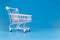 small pink pastel shopping cart on blue background. trolley at supermarket